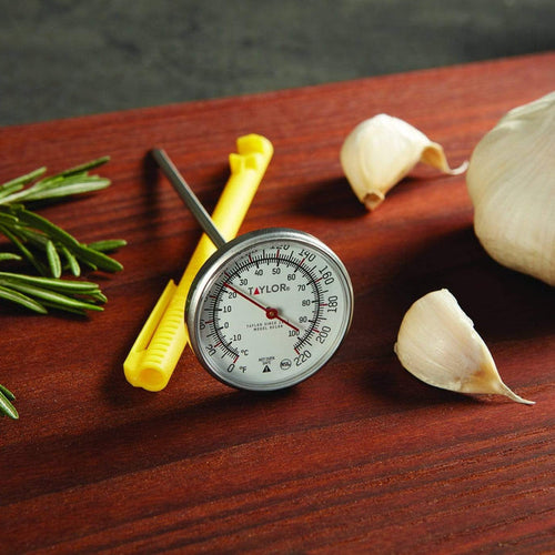1 3/4 inch instant read dial thermometer on a wooden surface with garlic cloves and rosemary
