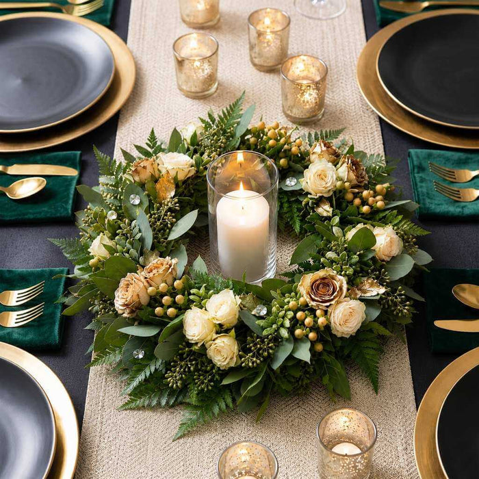 Green floral wreath centerpiece with a single pillar candle on a holiday table