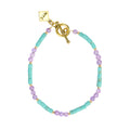 Bracelet with turquoise and purple beads and gold clasp on a white background