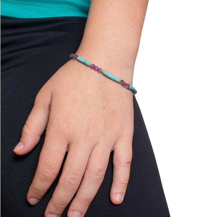 Hand wearing a colorful beaded bracelet on a plain background