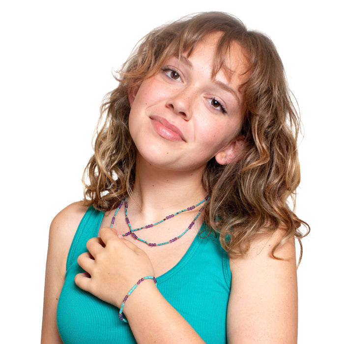 Young girl wearing a turquoise top with colorful jewelry on a white background