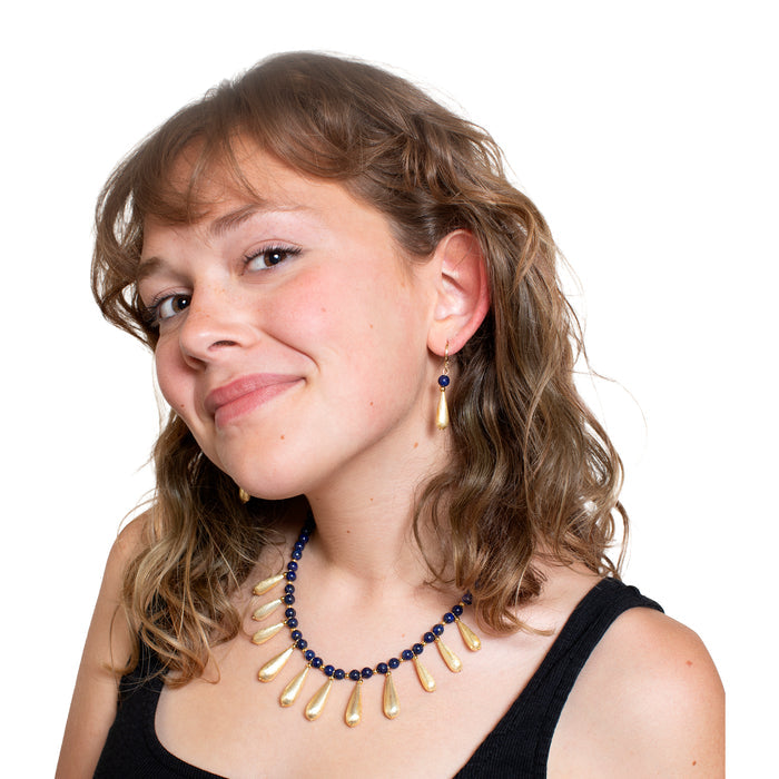 Woman wearing a gold and blue beaded necklace on a white background