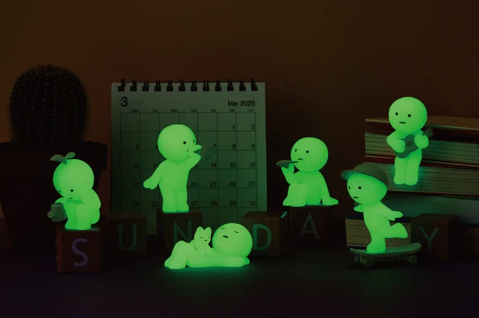 Smiski Sunday Series figurines, featuring a guitar-playing toy and other playful figures, glow green. Sold in blind boxes at Strangecat Toys.
