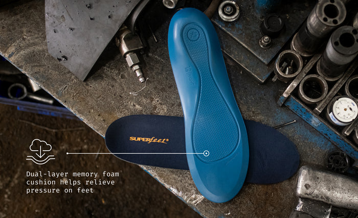 Superfeet's Work Memory Foam Insole against the top of a work desk. Text reads "Dual-layer memory foam cushion helps relieve pressure on feet".